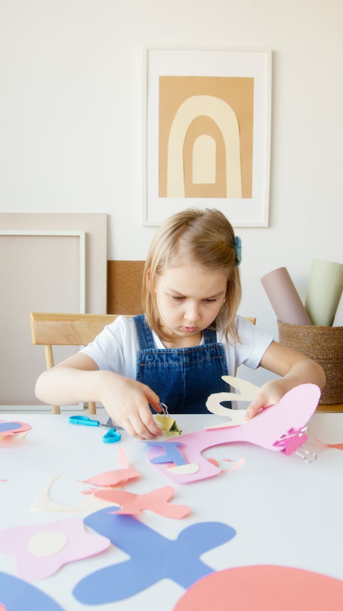 services-03 Young girl cutting colorful paper shapes for arts and crafts indoors.